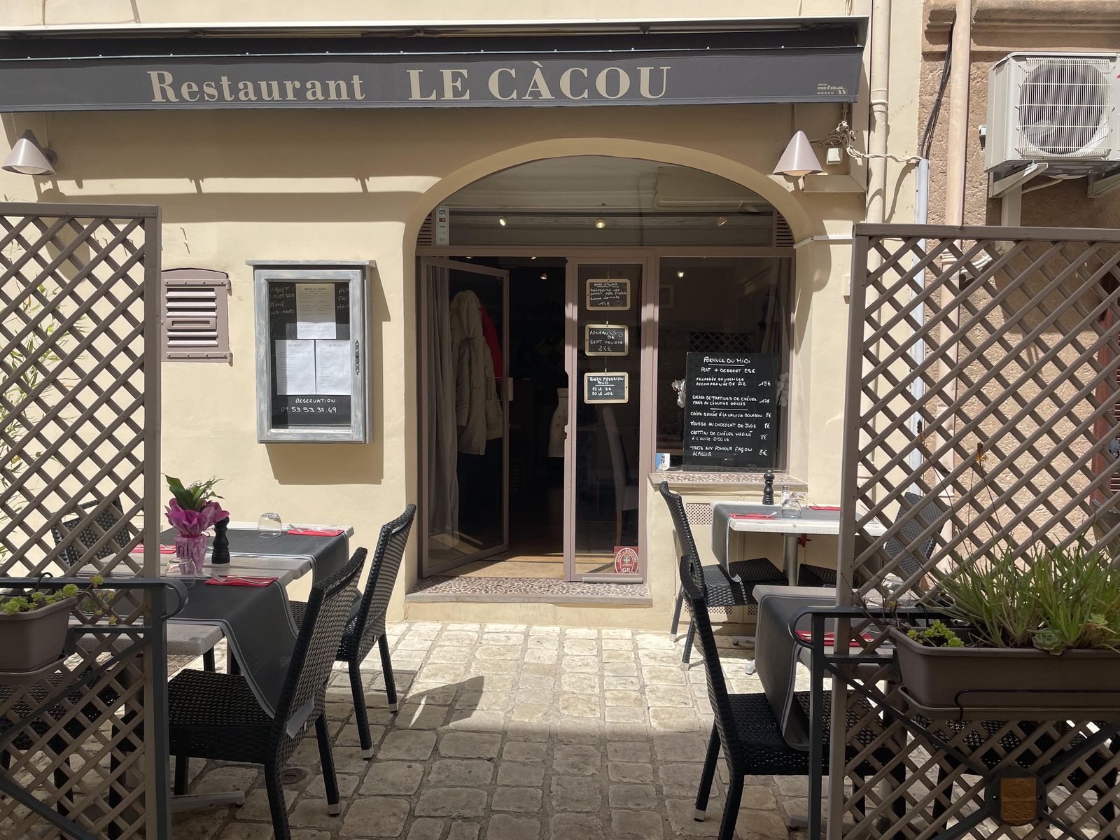 L'entrée du restaurant sous son arche, avec ses ardoises et sa terrasse