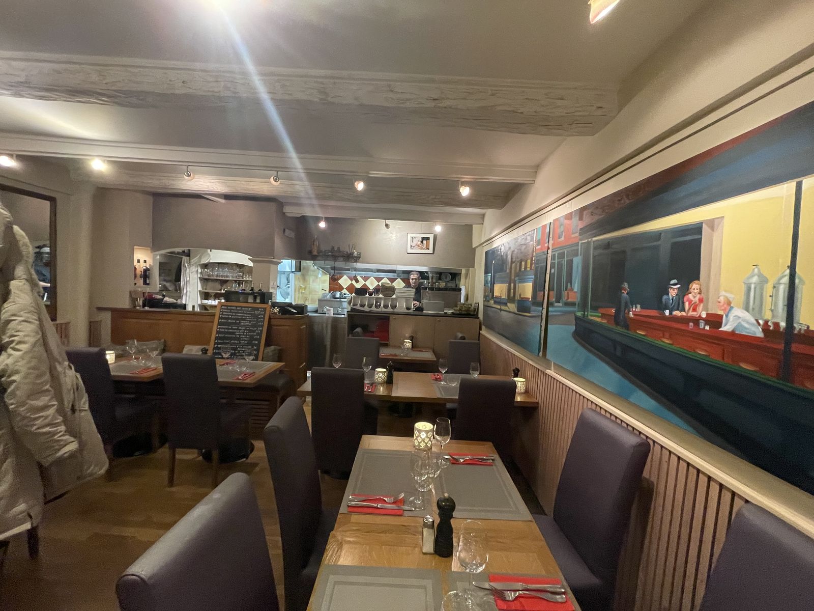 La salle du Càcou : tables dressées, banquette et grande fresque peinte qui court le long du mur